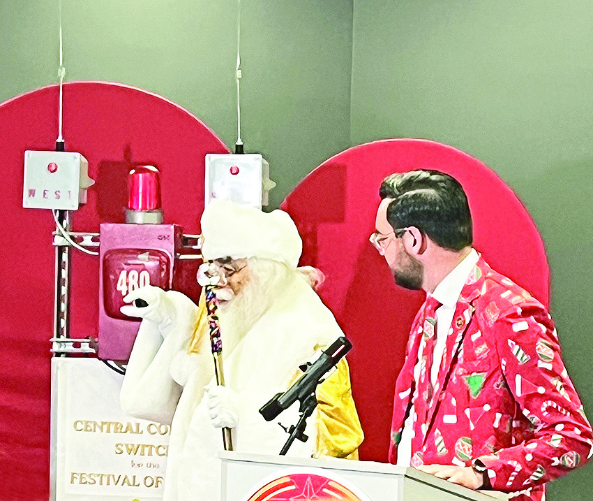 Decked out in his Christmas print suit, Van Erickson chats with Santa Claus at the kickoff for the 100th celebration news conference of the Natchitoches Christmas Festival.