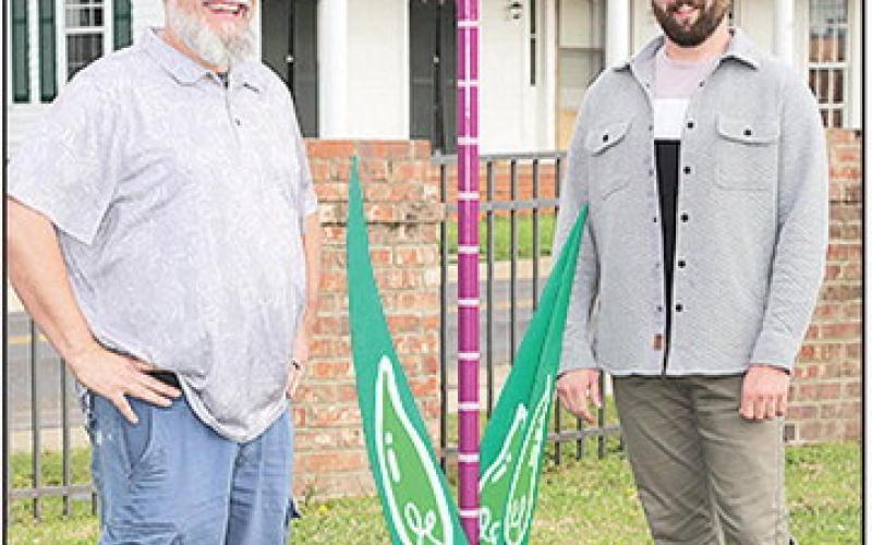 Cohver, at left, and McManus stand with the 8 ft Tulip sculpture unveiled in the courtyard outside the BOM Financial offices.