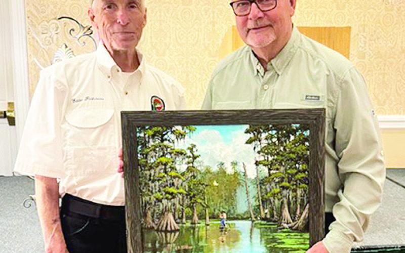 Gary Moore, of Many, left, was the successful bidder on Artist Eddie Pastureau’s original painting titled “Cruising the Swamp with Bandit.”