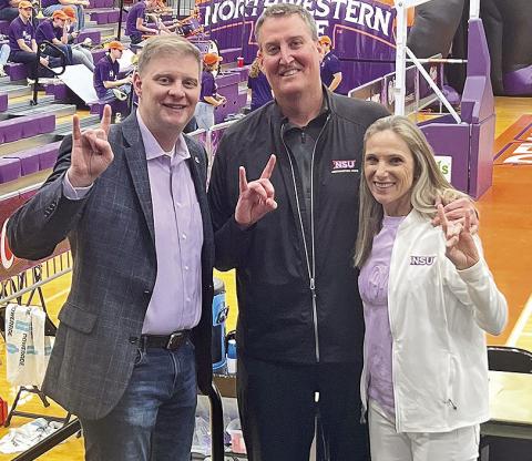 Alumni Eric (center) and Marylalyce Walsh Cox (right) pose with Northwestern State Director of Athletics Kevin Bostian during a Northwestern State basketball game. Submitted photo.