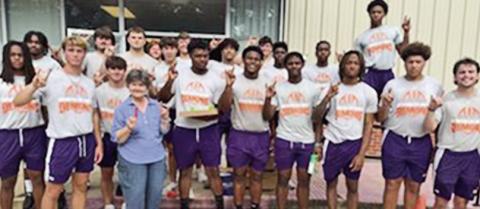 Football players and Green posing in front of the food pantry.