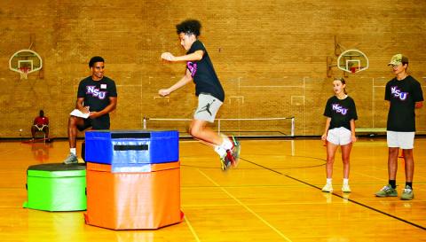 10th grader Braxton Cabrera participated in a jump test during Northwestern State University’s Sport Agility and Nutrition Camp while NSU graduate assistant Spencer Robinson and fellow campers looked on. Robinson is pursuing a master’s degree in Public Health and volunteers with the basketball program. Cabrera and other campers practiced skill-building and individualized plans for their sport and position.
