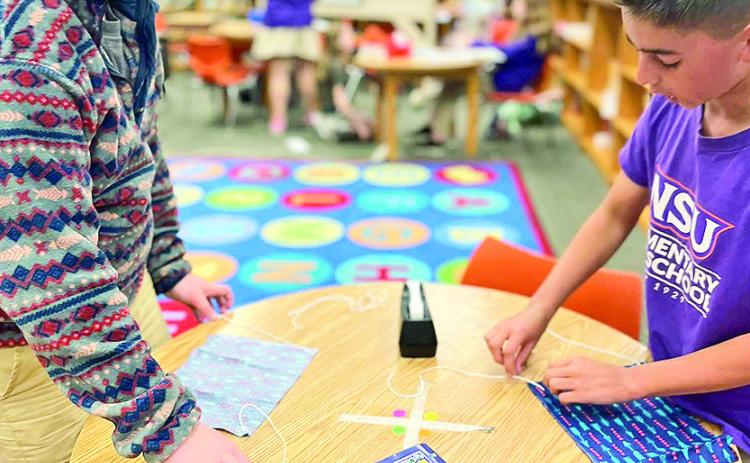 Moss Cain and Jude Coleman create a parachute using bits of fabric, yarn and tape.