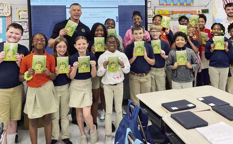 Jesse Taitano and Billy Clemons give The Lightning Thief books to 4th grade students at Natchitoches Magnet School.