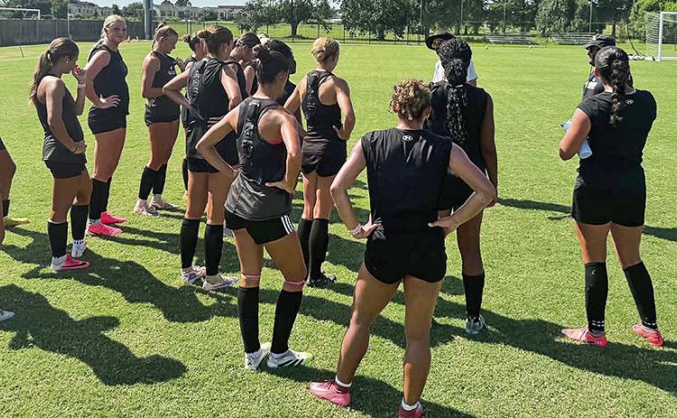 Head coach Ian Brophy (in gray) talks with the team before its first full practice on Monday evening at the Demon Soccer Field.