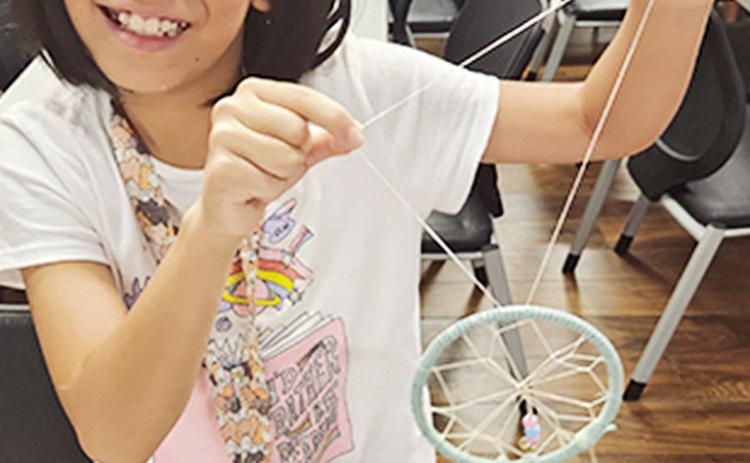 Yutai Yao proudly displays her handmade dream catcher at the interactive crafts workshop hosted by the Louisiana Folklife Center.