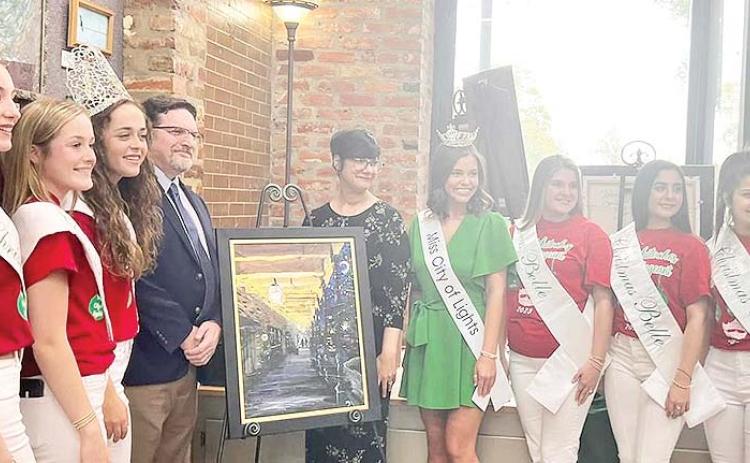 The Natchitoches Christmas Festival poster, painted by Matt Dawson, was unvelied Sunday at the Natchitoches Arts Council. He is pictured with Miss Merry Christmas and the Bells, and Miss City of Lights, along with his wife Amber.