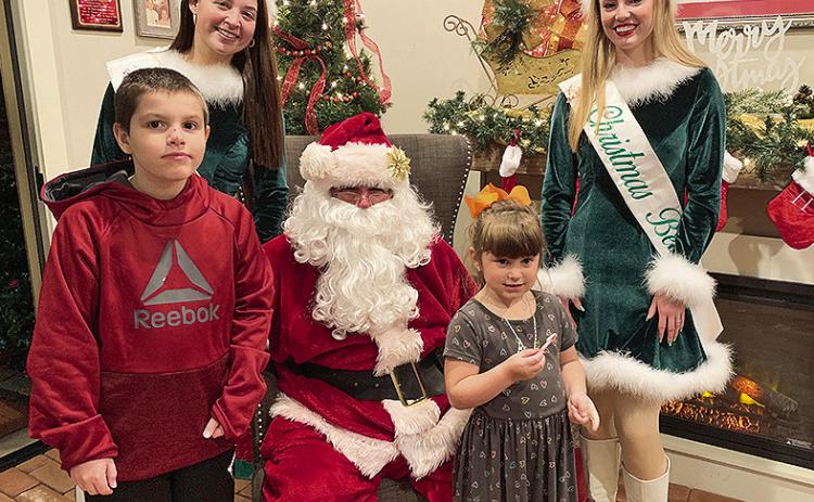 The Santa Claus House on the south end of Downtown Riverbank opened Sunday, Dec. 8, for the first night of the season. The first visitors were Gunner and Dixxie Hernandez from Winnfield. Pictured from left are Gunner, Christmas Belle Bess Stewart, Santa Claus, Dixxie and Christmas Belle Anderson Kelly. The Santa House remains open through December 23. Hours are 6-8:30 p.m.Sunday-Friday and 5-8:30 p.m. on Saturday.