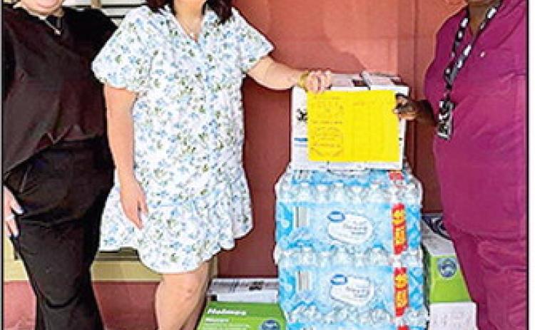 BOM donated desk fans and cases of water to Monica Evans in support of her community fan drive. The distribution date was June 21 in the St. Maurice community. From left are BOM’s Nicole Williams and Kristen Carpenter and Evans.