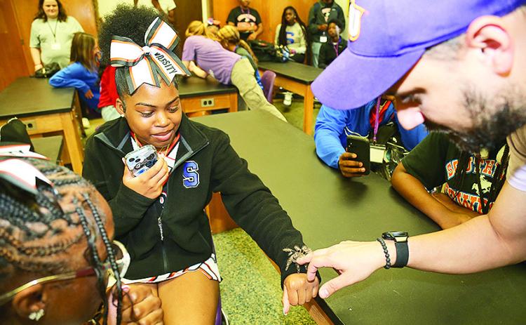 Corgan Stampley from Southwood High School braved an encounter with a Chaco Golden Knee tarantula during STEM Day at Northwestern State University. Stampley and classmates visited natural science labs to interact with arachnids, insects and reptiles while JD Cox, right, instructor in the School of Biological and Physical Sciences, discussed their importance in the environment.
