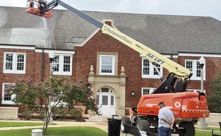 Matt Durr and Adam Edwards, owners of Natchitoches Exterior, pressure washed the roof of the Northwestern State Administrative Services building, formerly Caspari Hall, last Saturday. Malcolm Durr watching them.