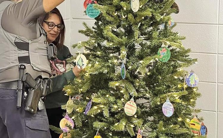 Erin Parish’s s art students at Natchitoches Magnet put their talent on display by creating ornaments for the school Christmas tree. School Resource Officer David Dorsey, and Secretary Necaia Solari put on the finishing touches.
