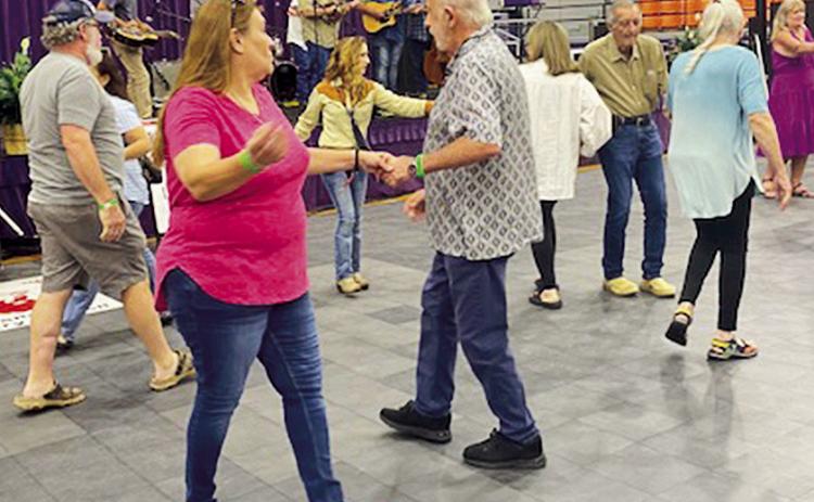 Twirlers join hands and walk in a circle during square dancing lessons with the Willie Stewart Family and Friends Bluegrass Band.