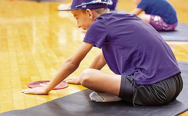 A camper participates in a flexibility exercise during Northwestern State University’s Sport Agility &amp; Nutrition Camp.
