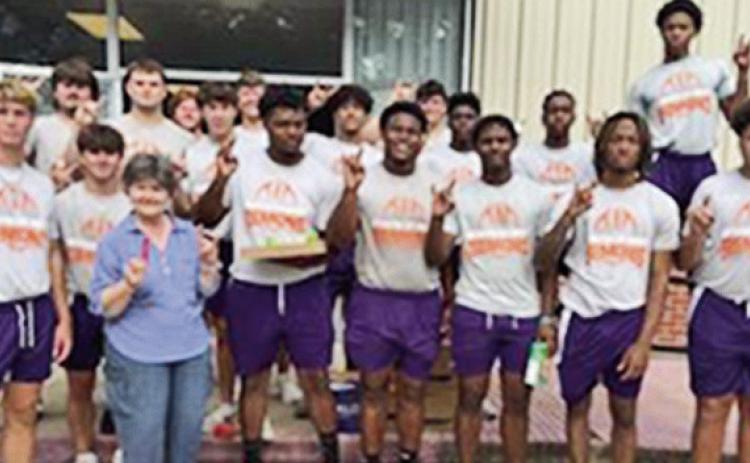 Football players and Green posing in front of the food pantry.