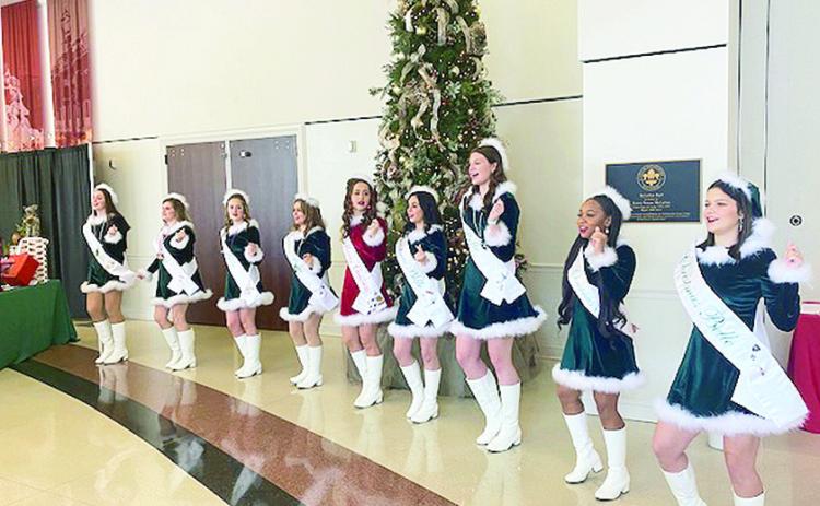 Miss Merry Christmas and the Belles perform a song and dance routine for the crowd. They adapt words to a Christmas jingle in what is a long standing tradition.