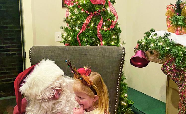 Santa Claus greets four-year-old Riley Rucker of Natchitoches on the Riverbank Wednesday night to hear her Christmas wishes. Riley is the daughter of Peyton and Ainsley Rucker. The Santa House remains open through Dec. 23. Hours are 6-8:30 p.m. each night.