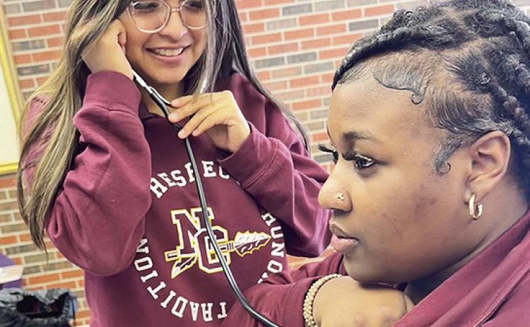 Gabriela Contreras, standing, listened to vita signs of Azmir Johnson during a workshop on nursing occupations at Friday’s ACE Healthcare event. Both students attend NCHS and both are interested in discovering more about healthcare careers.