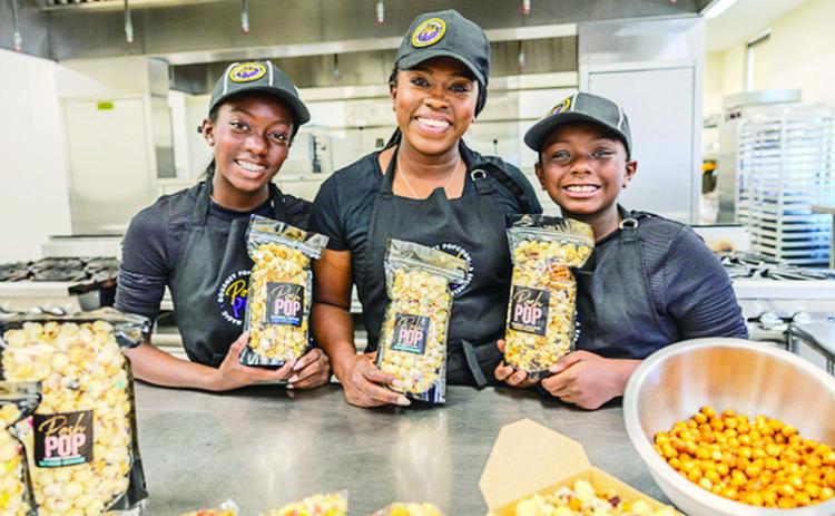 Posh Pop “kidpreneur” sisters Harper, left, and Bailey Galloway mix batches of Cheesy Cheddar Bomb popcorn in the FOODii industrial kitchen. FOODii provides a number of services for food-based startup companies, such as food safety training and marketing assistance. Photo by V. Todd Miller/LSU AgCenter