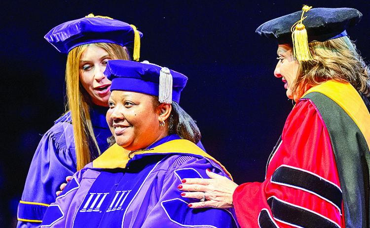 Dr. Sharonda Johnson, center, is hooded by Dr. Aimee Badeaux and Dr. Robyn Ray during the commencement ceremony in which she earned the Doctor of Nursing Practice degree.