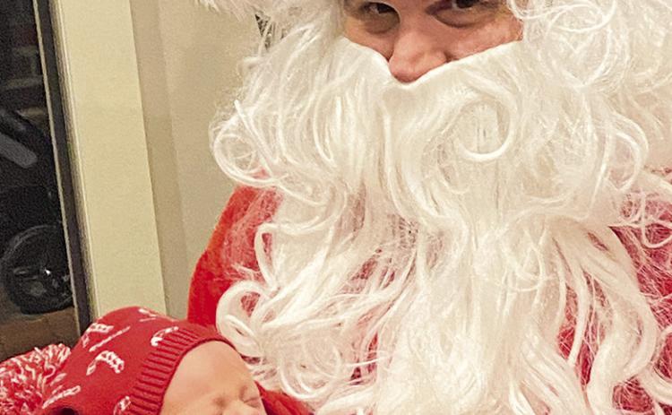 Newborn Felicie Wyble pays her first visit to Father Christmas inside the Santa House on the Downtown Riverbank Monday. The week-old child is the daughter of Chris Wyble and Brooke Parrent of Alexandria. The photo was snapped by Times Editor Nora Drenner, the grandmother.
