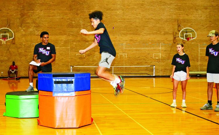 10th grader Braxton Cabrera participated in a jump test during Northwestern State University’s Sport Agility and Nutrition Camp while NSU graduate assistant Spencer Robinson and fellow campers looked on. Robinson is pursuing a master’s degree in Public Health and volunteers with the basketball program. Cabrera and other campers practiced skill-building and individualized plans for their sport and position.