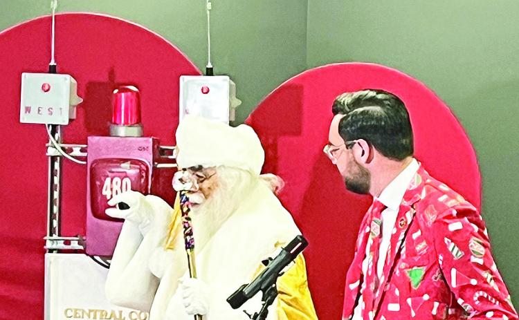 Decked out in his Christmas print suit, Van Erickson chats with Santa Claus at the kickoff for the 100th celebration news conference of the Natchitoches Christmas Festival.