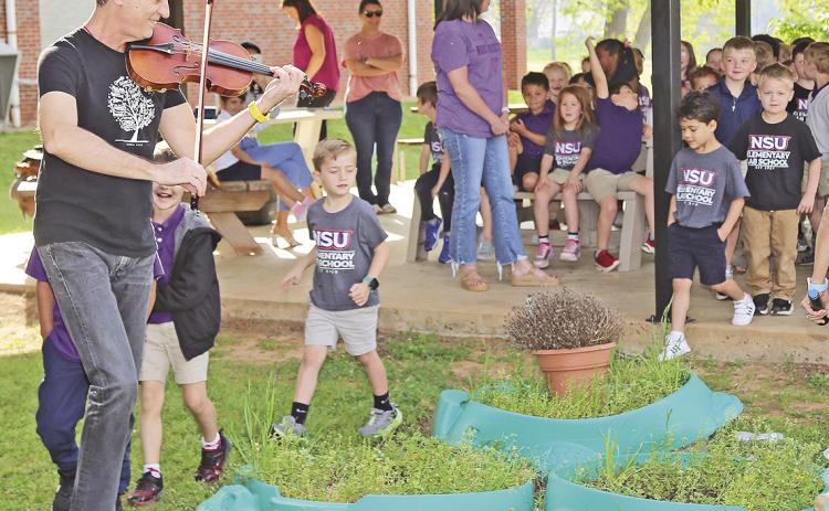 NSU Professor of Music Dr. Andrej Kurti played “The Pea Patch Jig” while leading a procession through the school garden at NSU Elementary Lab School.