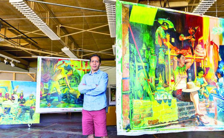 Artist Edgar Cano is pictured with three of his large paintings.