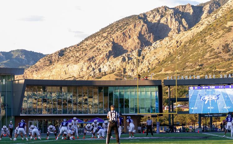 Northwestern State football stands at the line of scrimmage in the game at Weber State with the mountains of the Wasatch Range in the background.